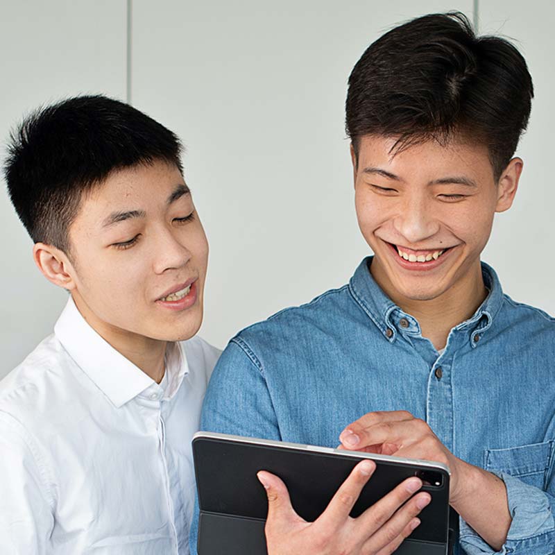 two men smiling while looking at a tablet